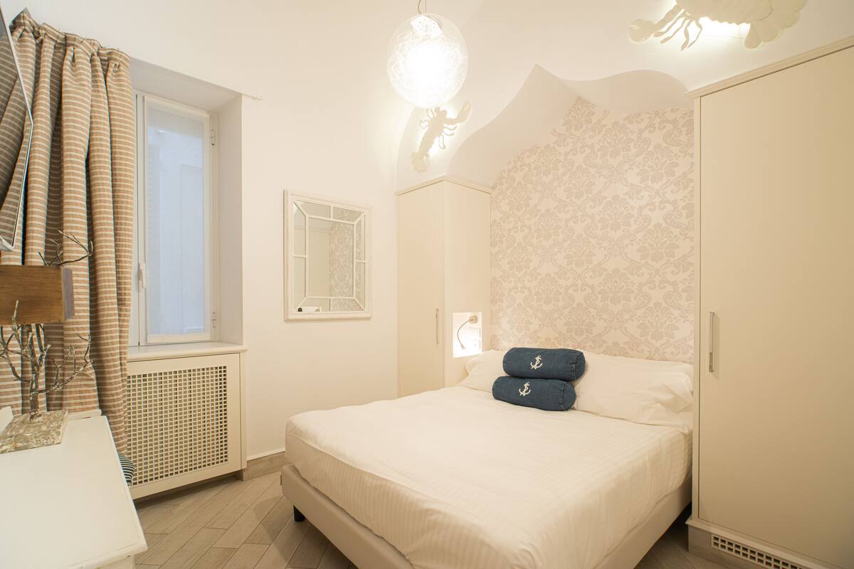 A bedroom with a bed, a window, a radiator, and a wardrobe.