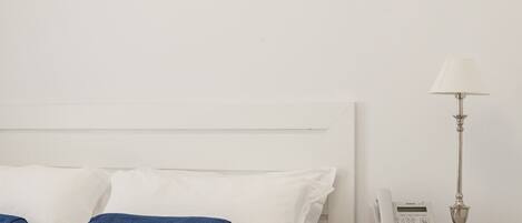 A bedroom with a bed, pillows, a bedside table with a lamp, and a phone.