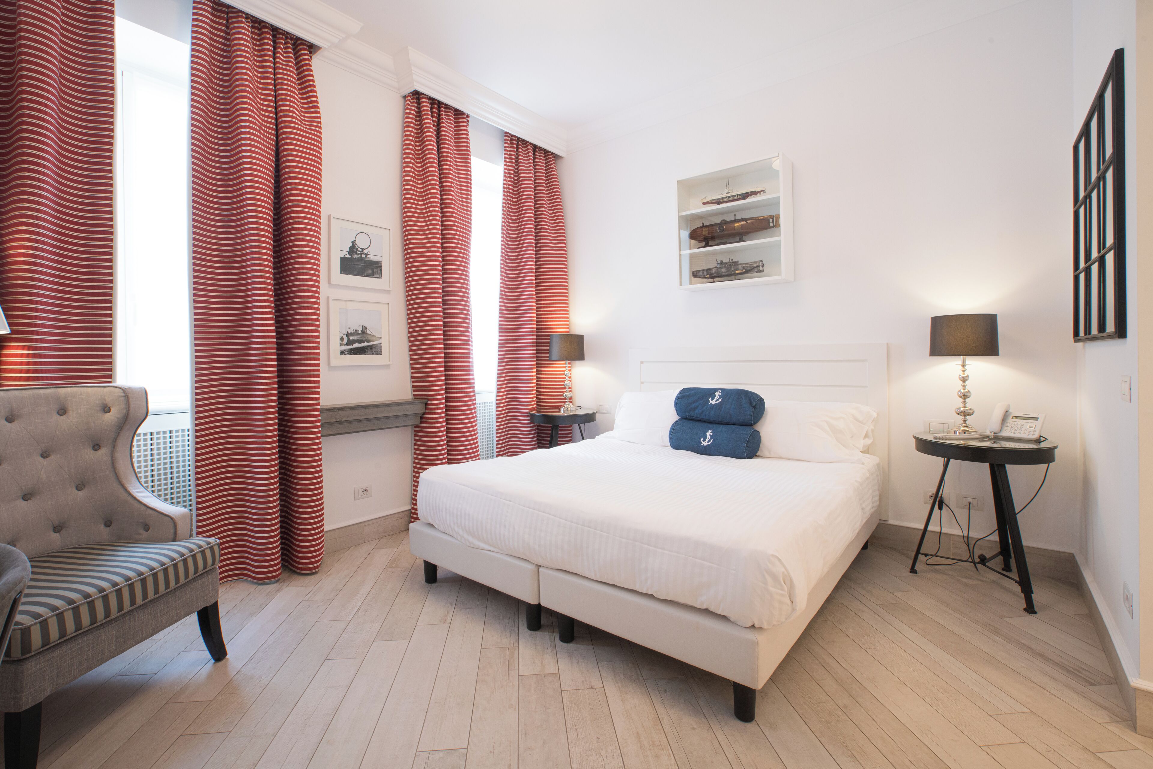 Une chambre d’hôtel avec un grand lit, une chaise, une table de chevet avec une lampe et une étagère murale agrémentée d’objets décoratifs.