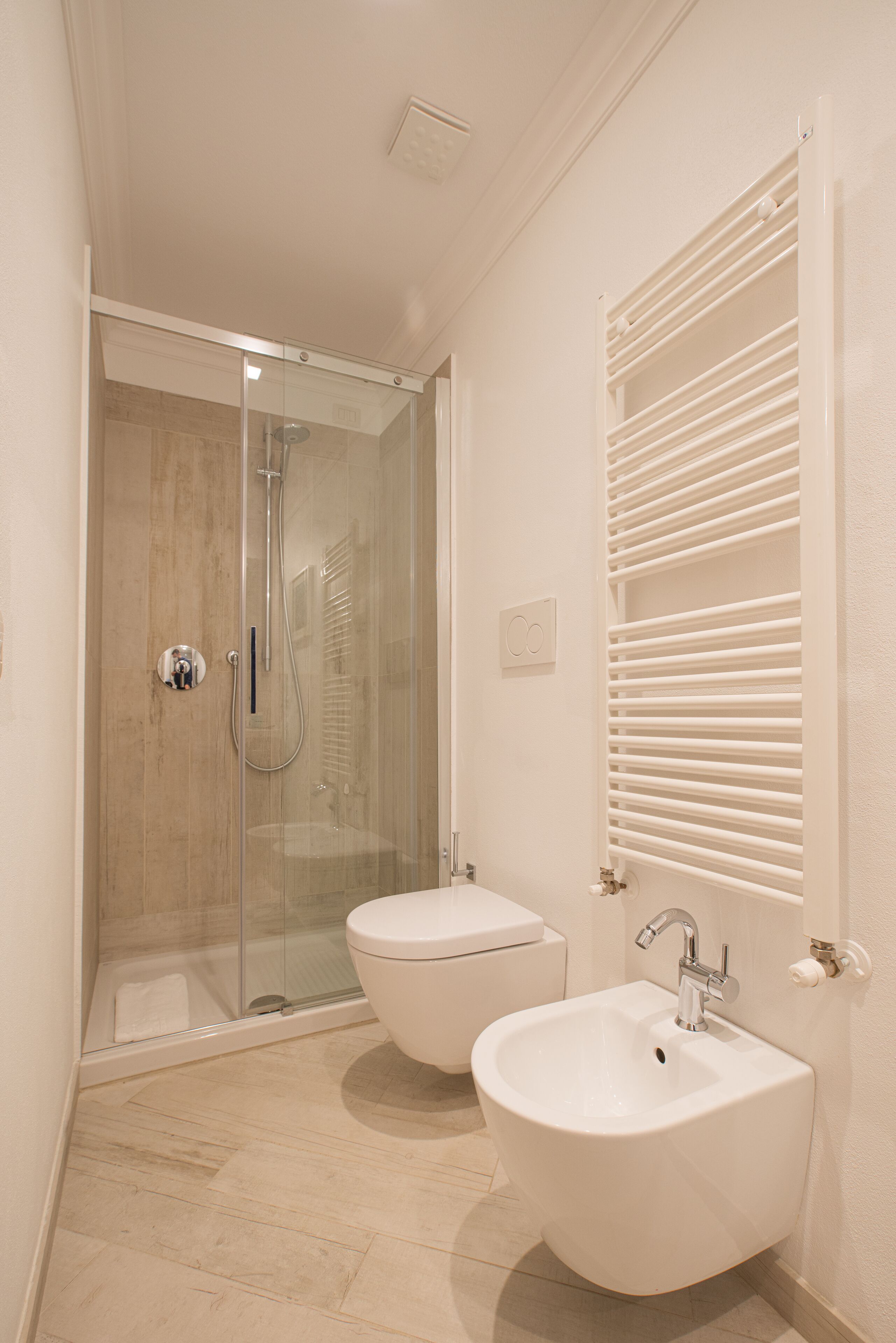 Un baño con ducha compartimentada por vidrio, inodoro y lavamanos.