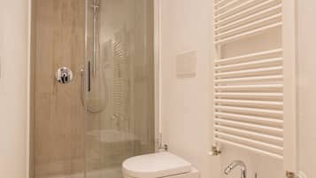 Un baño con ducha compartimentada por vidrio, inodoro y lavamanos.