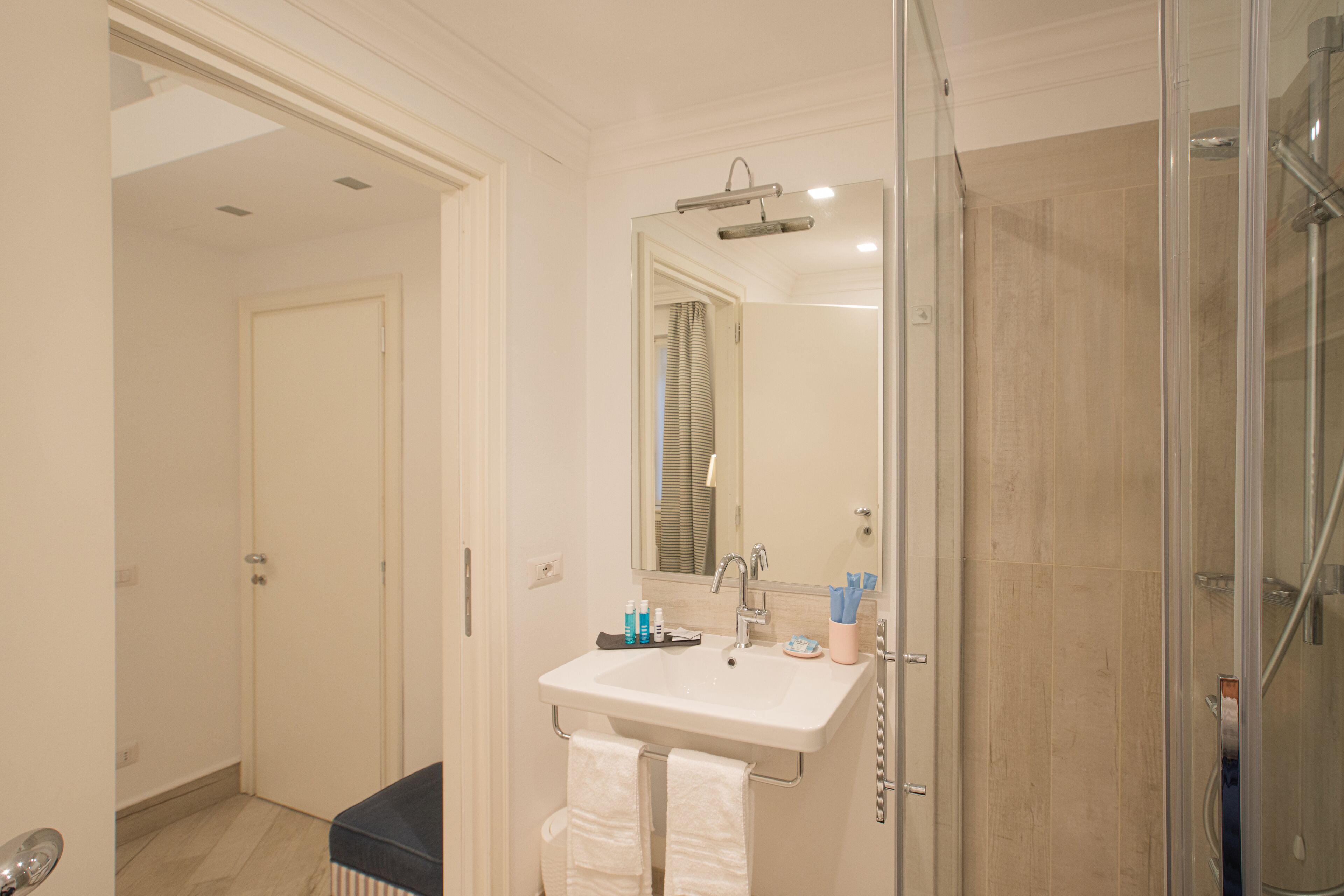 Un baño con lavamanos, espejo y ducha blancos.