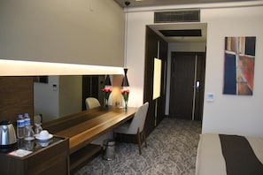 A hotel room with a wooden desk, a chair, a bed, a lamp, and a painting on the wall. - Armoni Park Otel (Kastamonu)