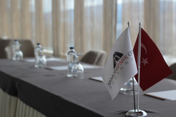 Una mesa de conferencias con banderas y placas de identificación, lo que sugiere un ambiente formal para una reunión.