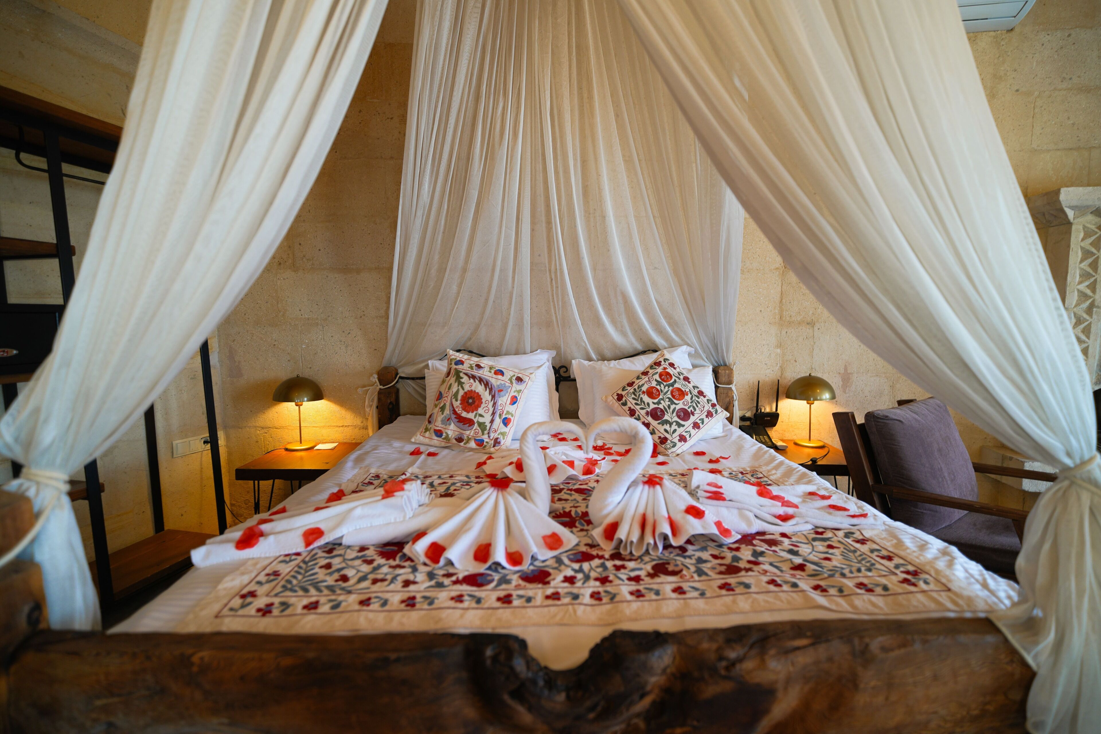 Cama com dossel, almofadas e arranjo decorativo de toalhas em formato de cisne.