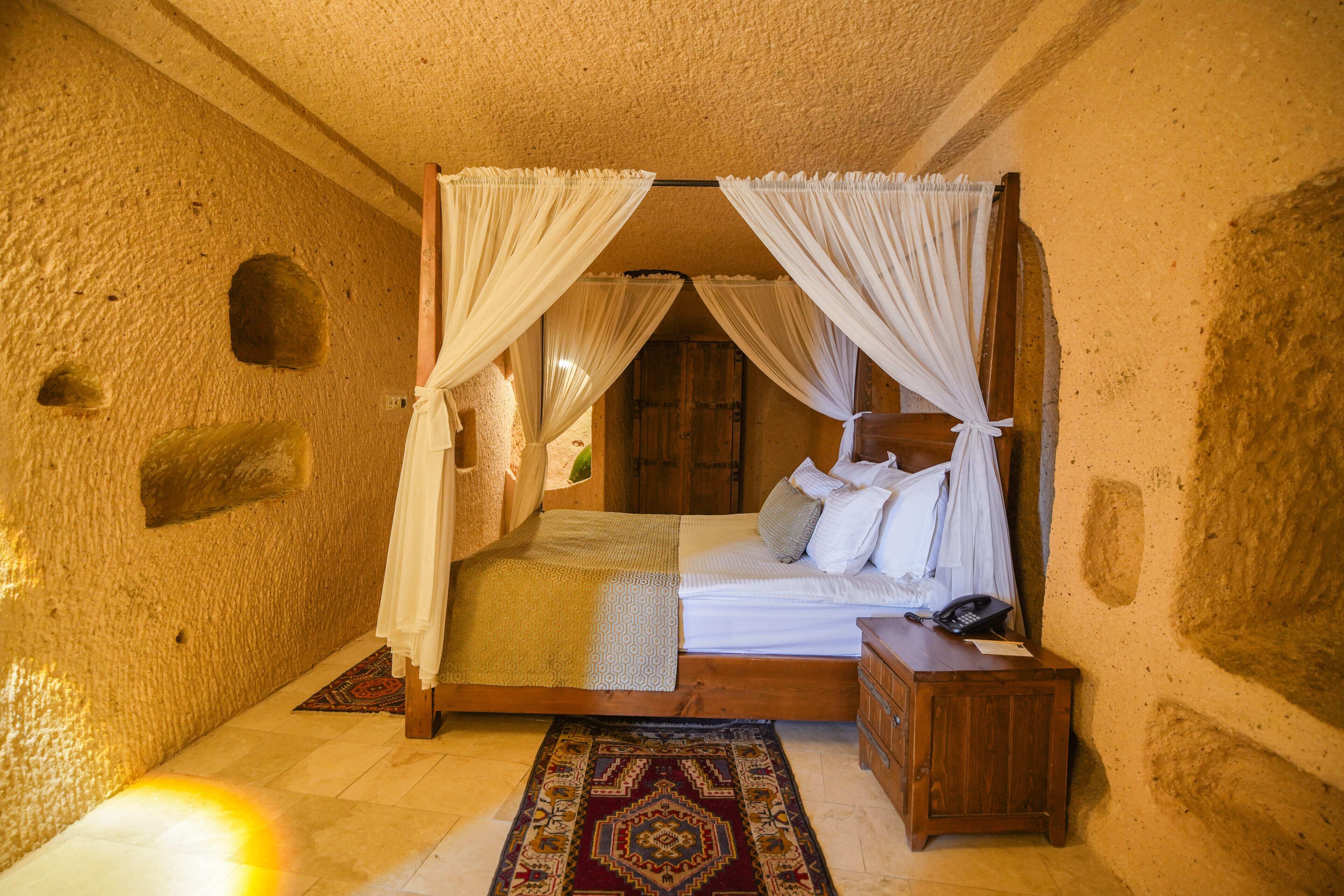 A room with a bed, a nightstand, a telephone, and a patterned rug.