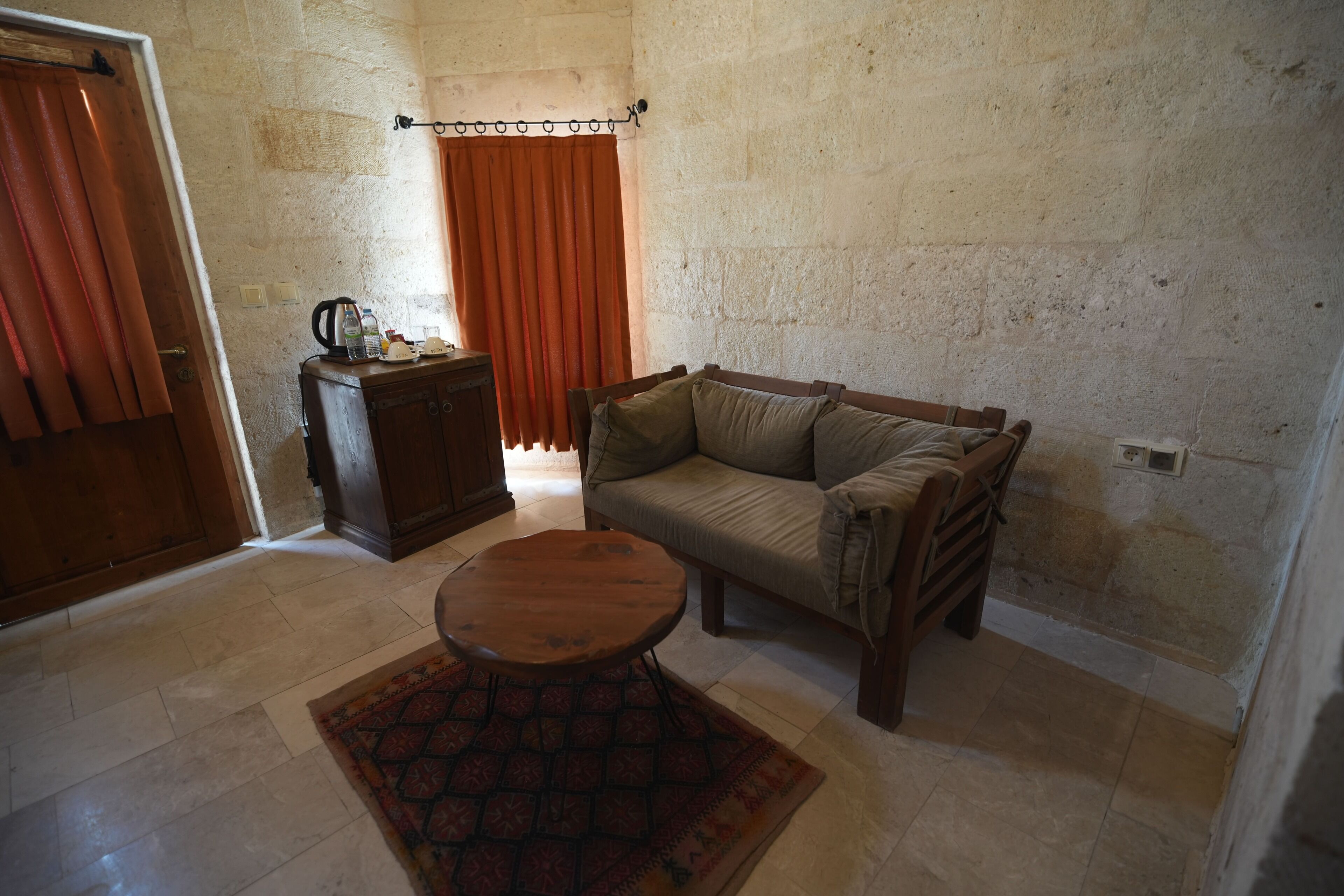 A living room with a sofa, a small table, a cabinet, and a patterned rug.