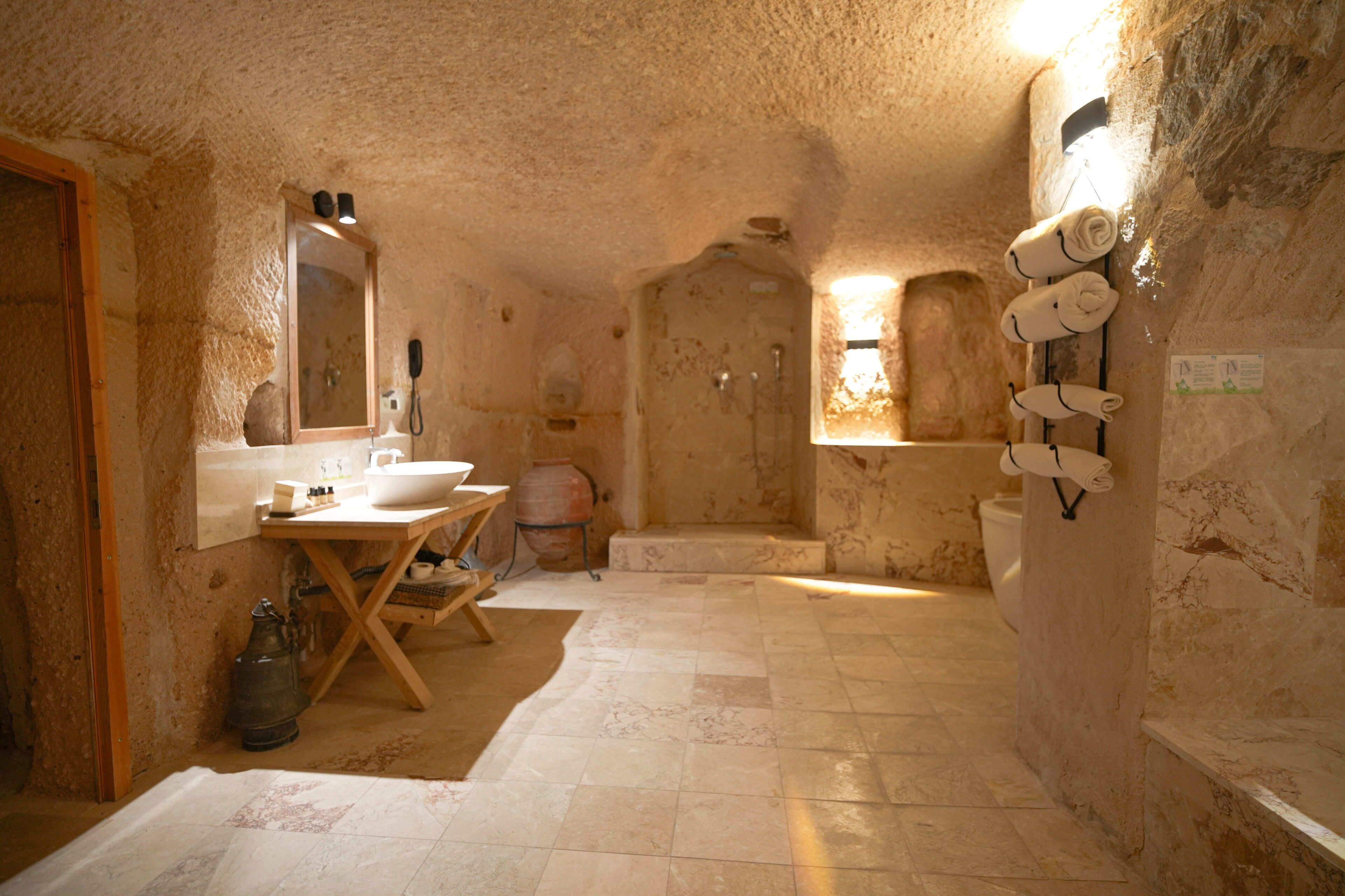A rustic bathroom with a wooden vanity, a large mirror, a sink, and a bathtub.