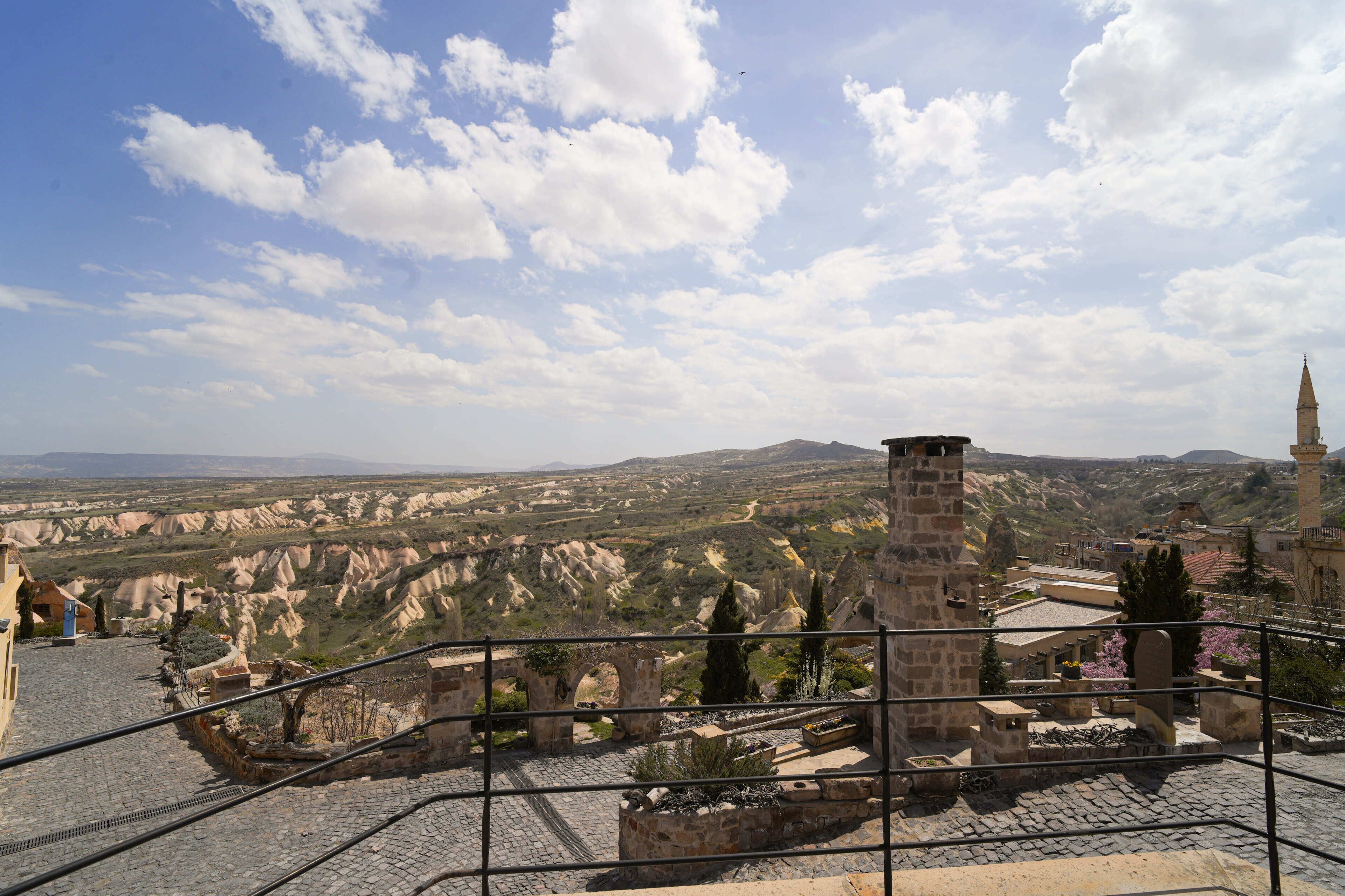 A stone staircase leading to a terrace with a view of a mountainous landscape and a church tower.