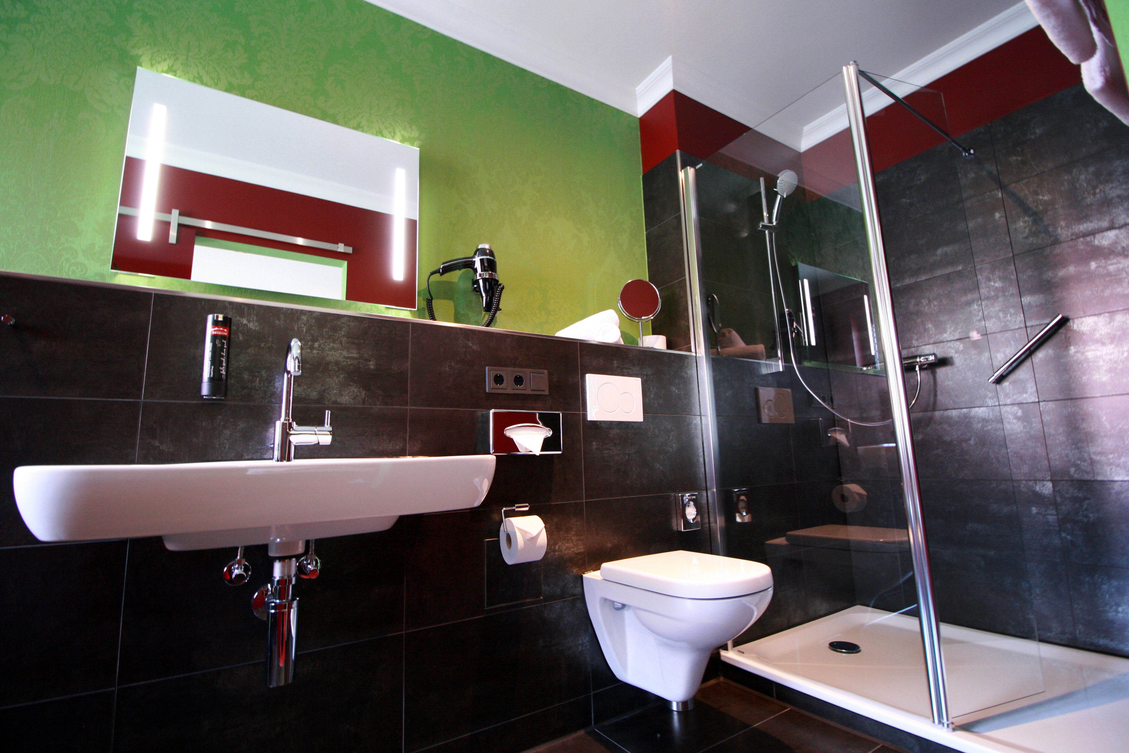 A modern bathroom with a white sink, toilet, and glass-enclosed shower.