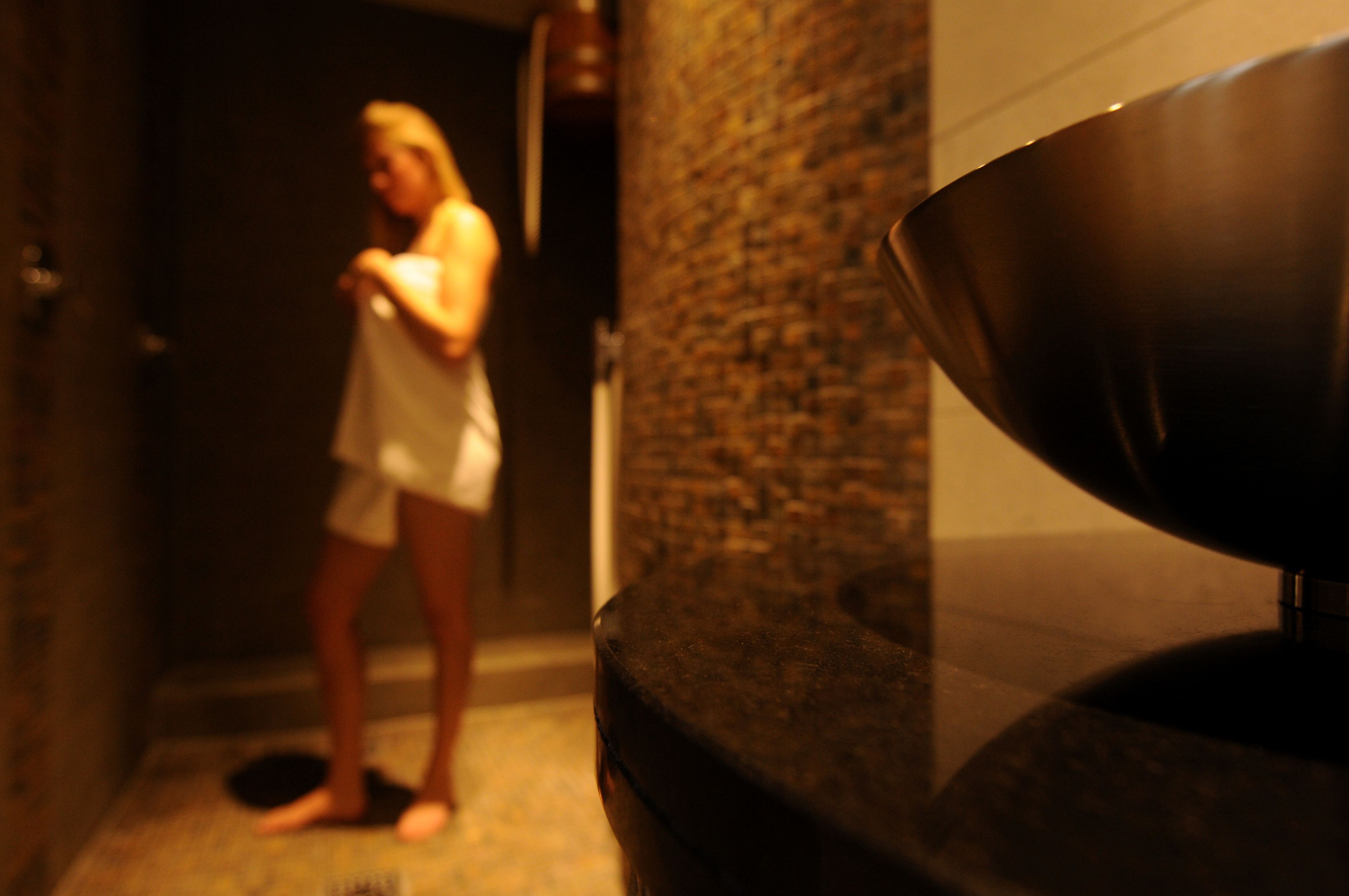 A bathroom with a stone wall and a large bowl on a countertop.