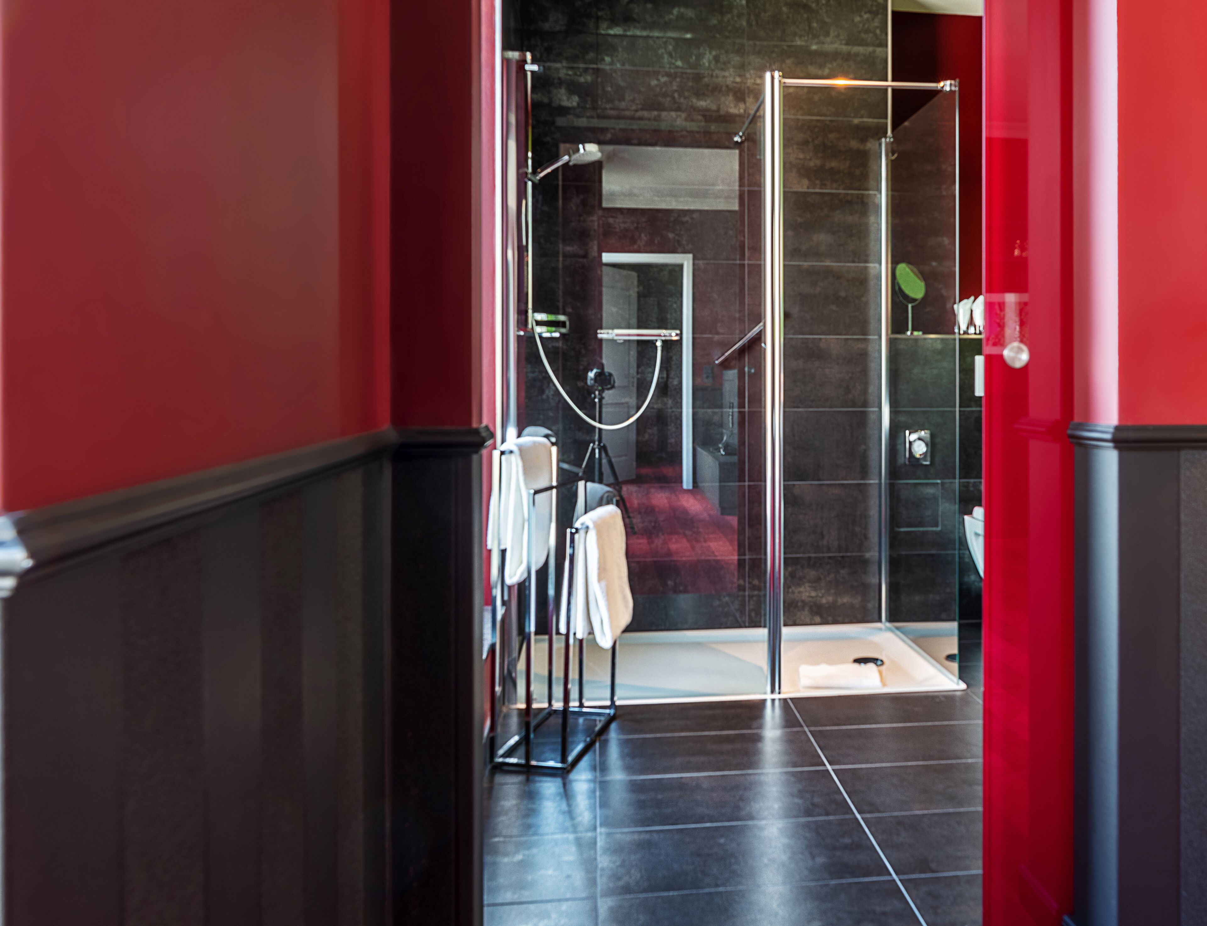 A modern bathroom with a glass shower enclosure, a towel rack, and a visible toilet.