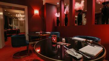 A dimly lit room with a round table set for dining, a blue chair, and a red carpet.