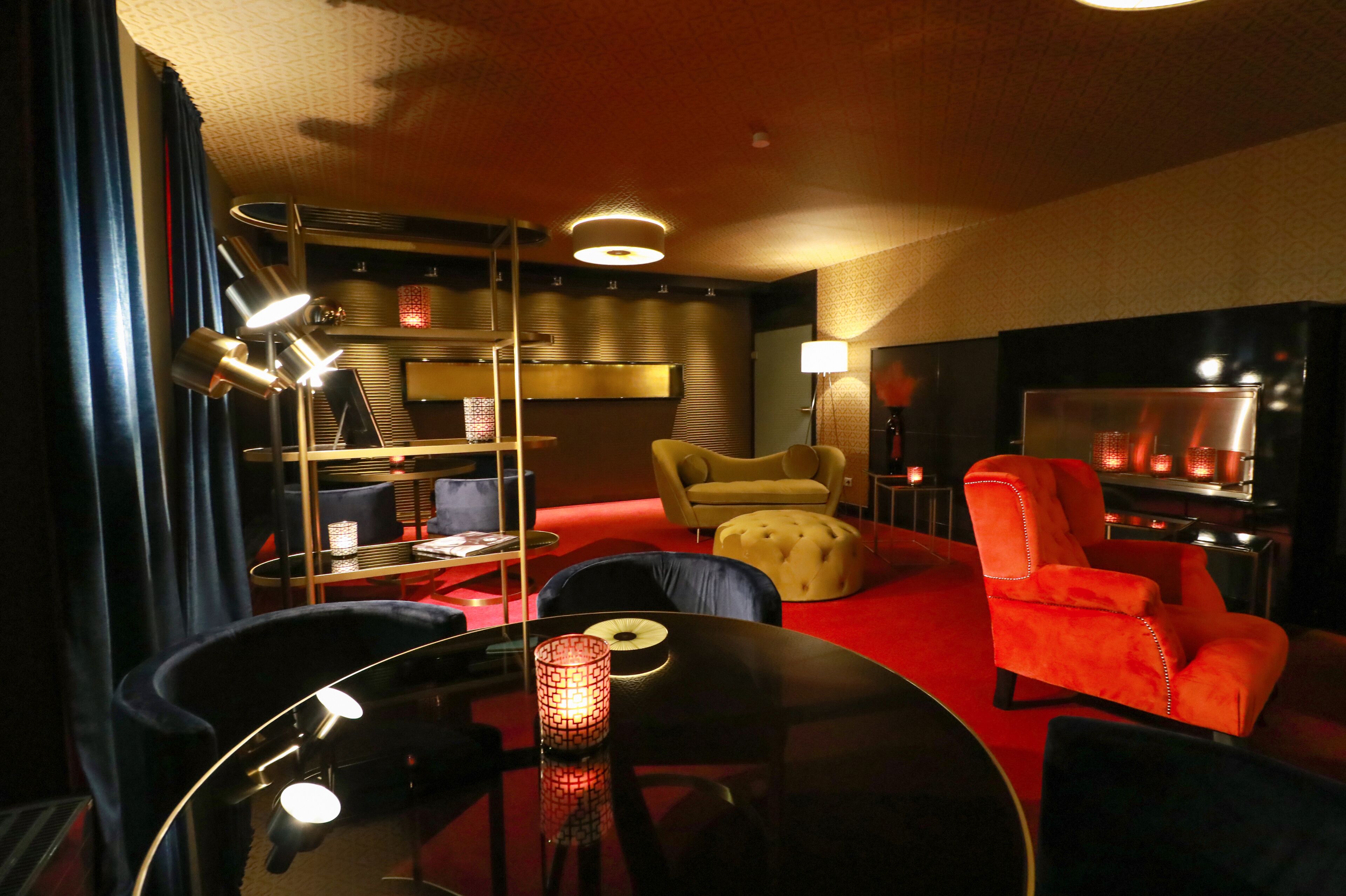 Una sala de estar moderna con alfombra roja, una mesa redonda, un sofá, un sillón rojo y una estantería.