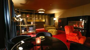 Una sala de estar moderna con alfombra roja, una mesa redonda, un sofá, un sillón rojo y una estantería.