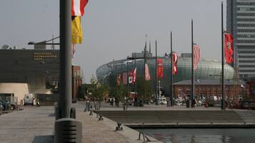 A stadium with multiple flags, a water body, and a building labeled "DEUTSCHES AUSWANDERER HAUS".
