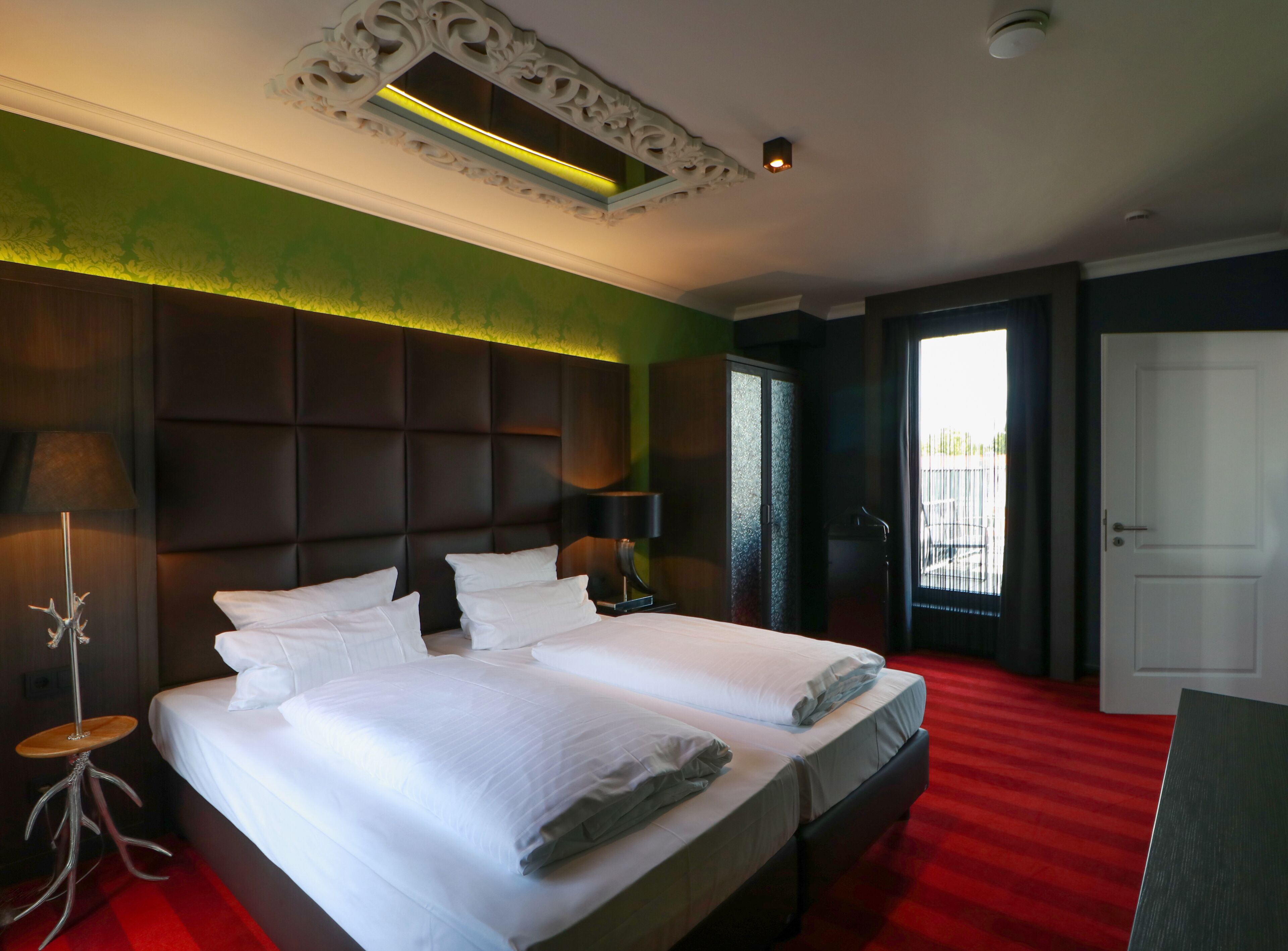 Una habitación de hotel con una cama grande, una mesita de noche, una lámpara y un armario.