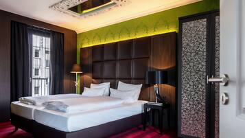 A modern hotel room with a large bed, a nightstand, a lamp, and a decorative door.