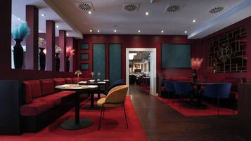 Ein modernes Restaurant mit roter und türkiser Einrichtung, das eine lange Theke, Sitzbereiche und dekorative Vasen zeigt.
