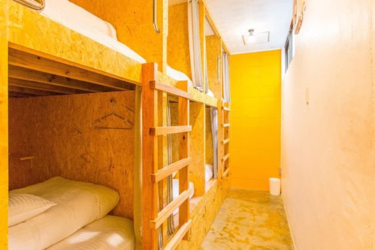 A narrow corridor with bunk beds on one side and a small bathroom area on the other.