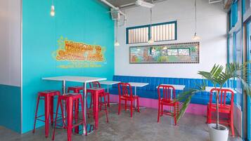 A vibrant hostel interior with teal walls, red chairs, and a mural welcoming guests.