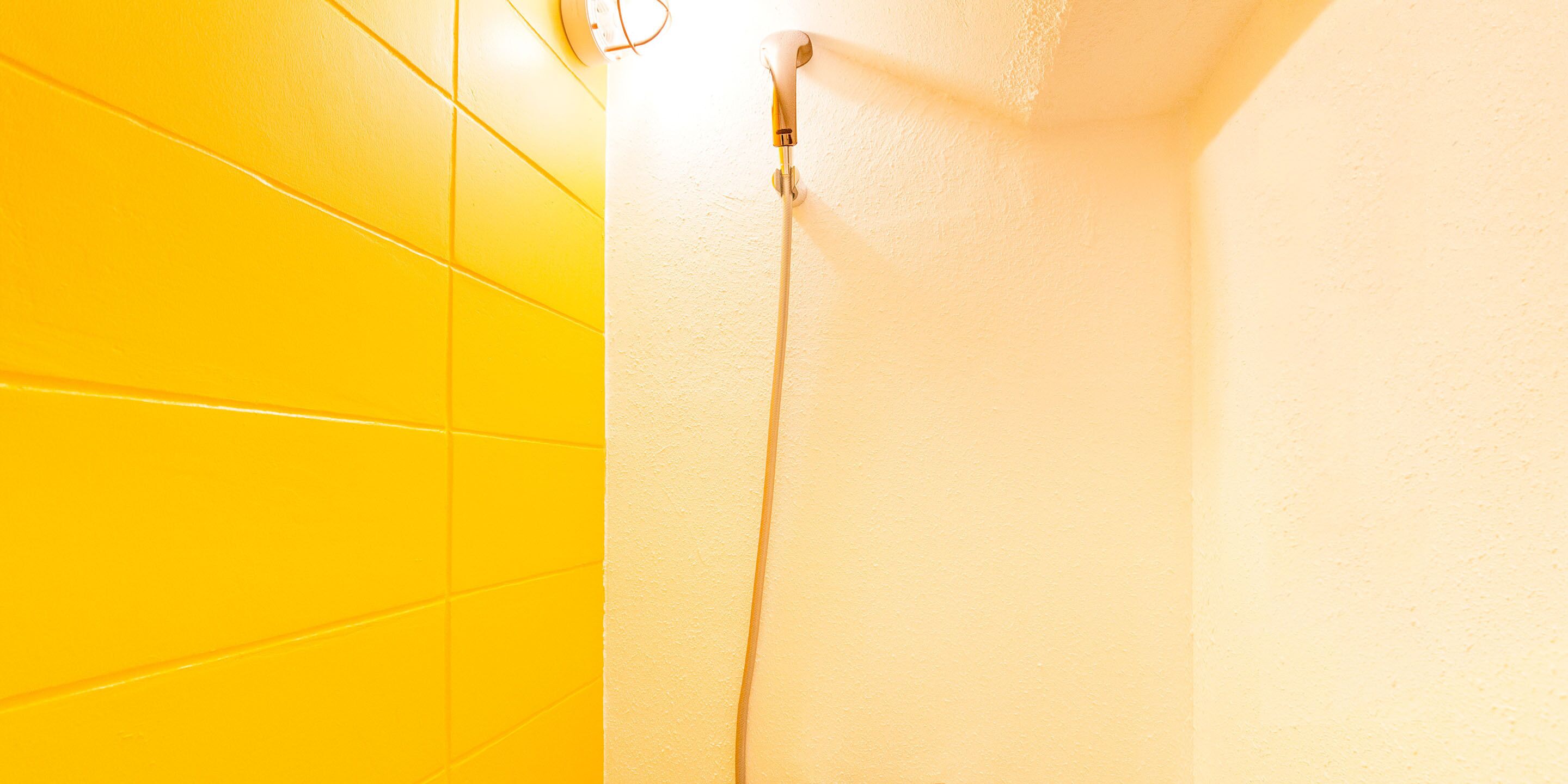 A corner of a room with yellow tiles and a white wall.