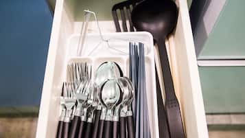 A drawer containing various utensils including forks, spoons, and a black spatula.