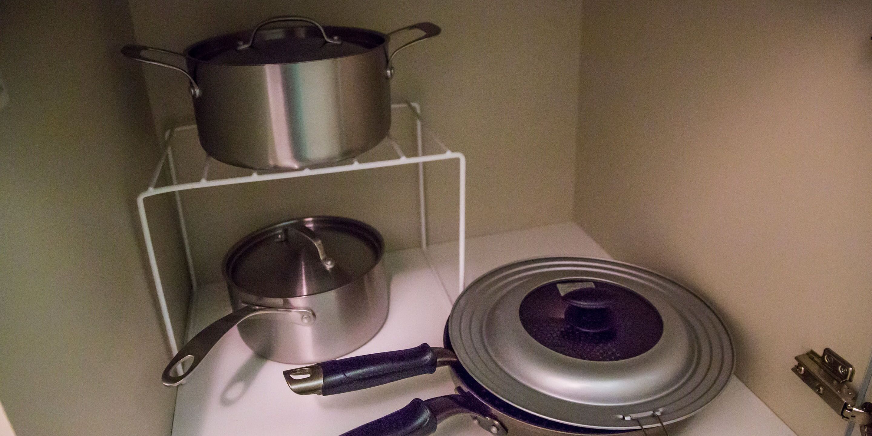 A kitchen with a white countertop, a pot rack, and a stove.