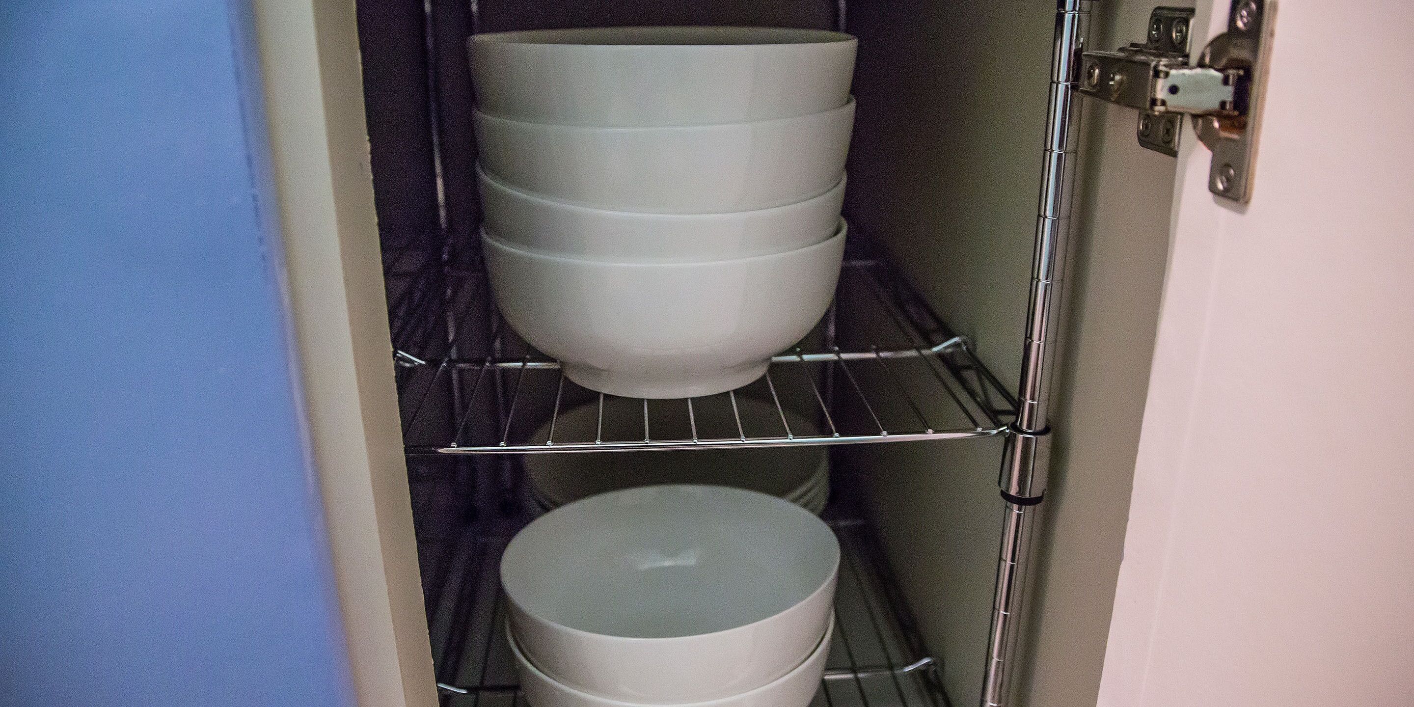 A storage unit with shelves holding white bowls.
