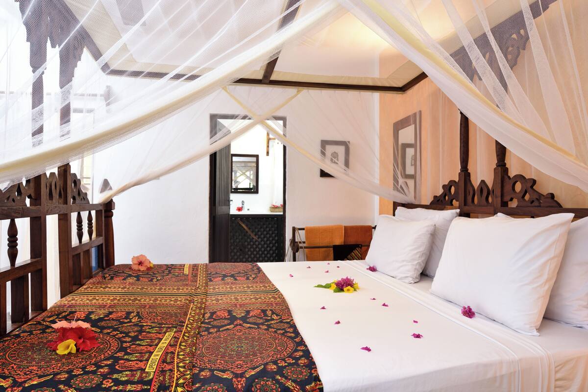 Una habitación con cama, dosel y vistas al exterior.