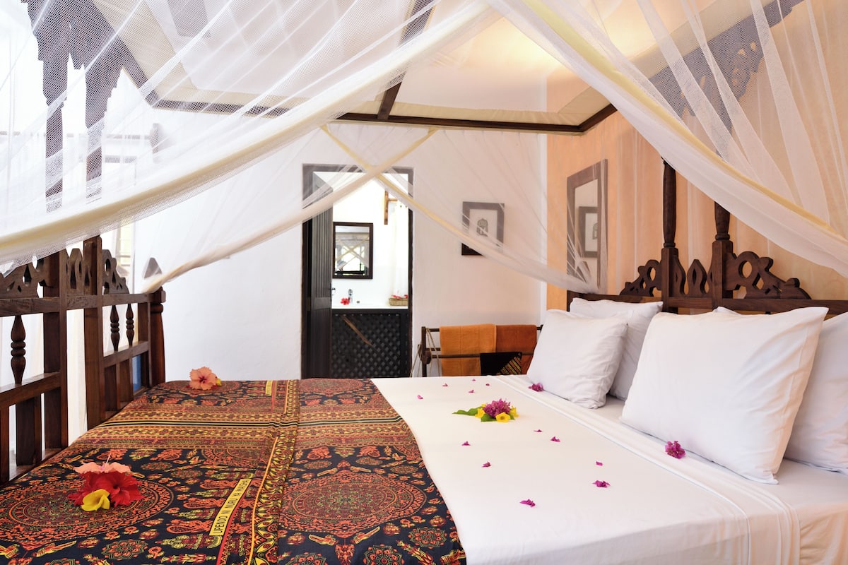 A room with a bed, a canopy, and a view of the outside.