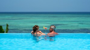 A couple in a clear blue pool with a drink and a lemon slice on the edge. - Shooting Star Boutique Hotel (Kiwengwa)