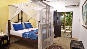 A bedroom with a bed under a mosquito net, a ceiling fan, and a door leading to an outdoor area. - Shooting Star Boutique Hotel (Kiwengwa)