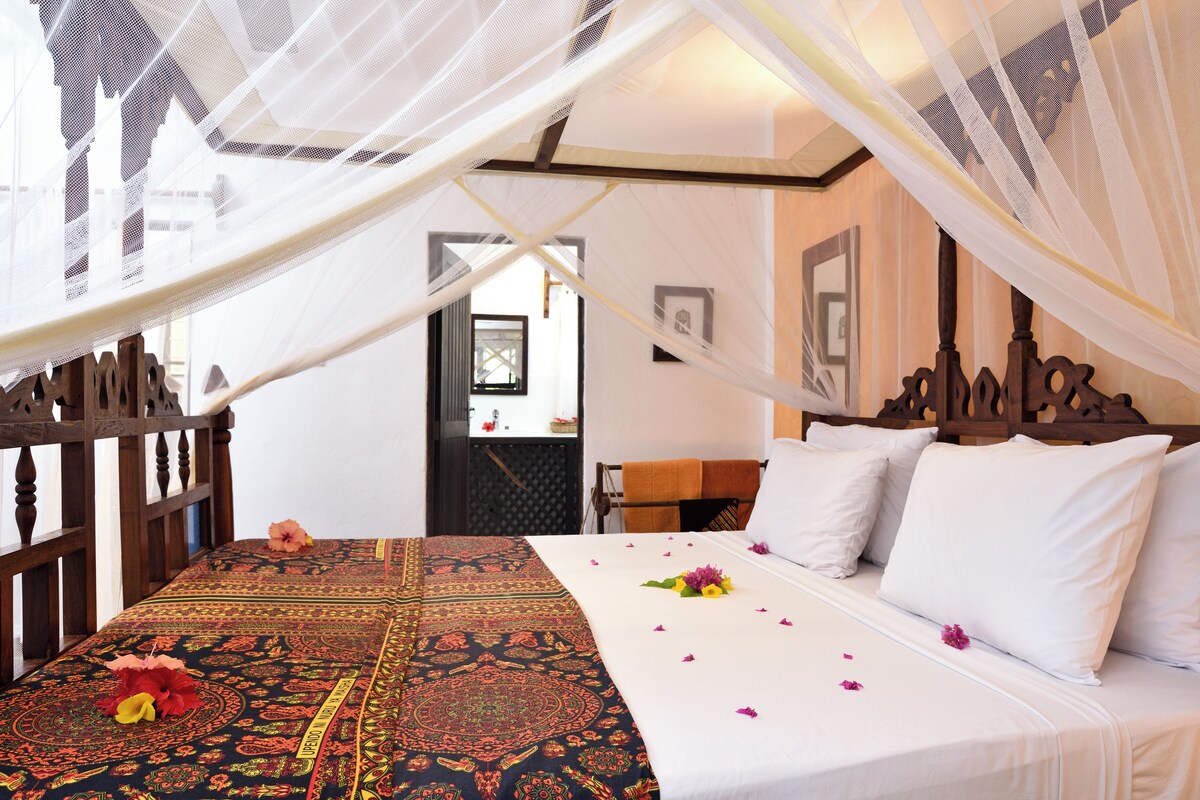 Una habitación con cama, dosel y vistas al exterior.