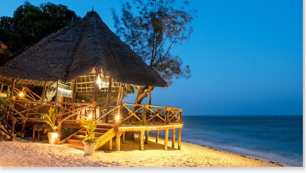 A beach hut with a thatched roof, wooden deck, and potted plants. - Shooting Star Boutique Hotel (Kiwengwa)