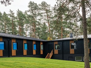 Moderni rakennus, jossa on musta julkisivu, puuelementtejä ja suuret ikkunat.