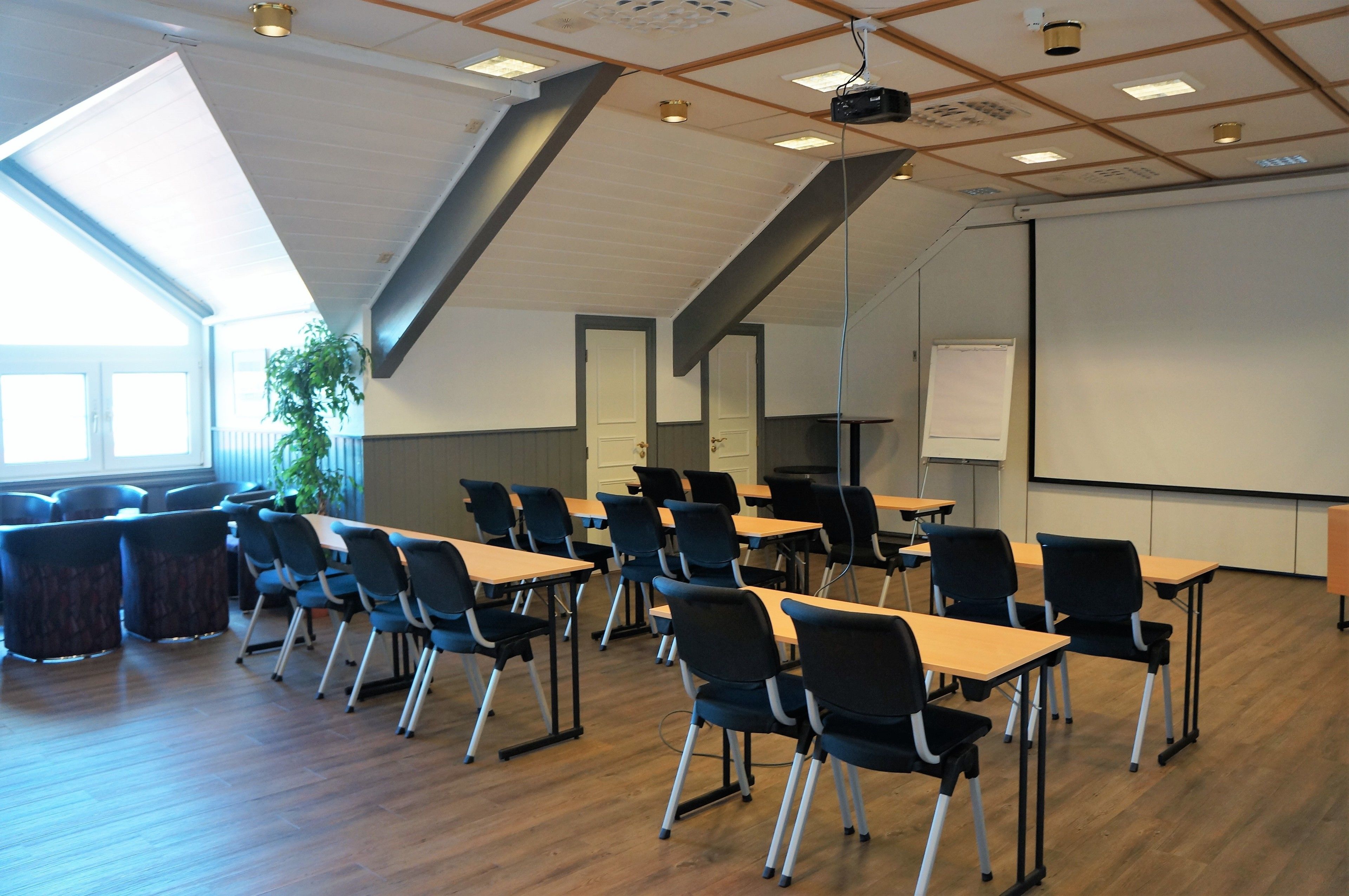 A conference room with wooden tables and chairs, a projector, and a whiteboard.