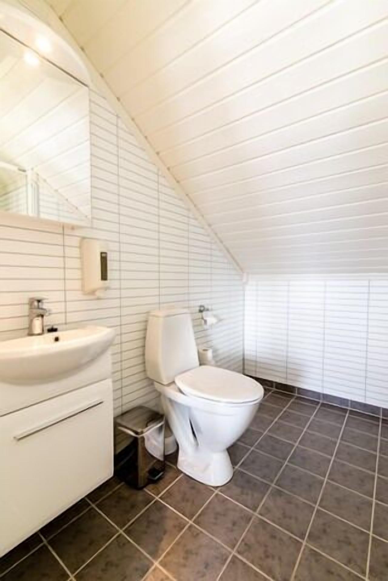 A modern bathroom with a white sink, toilet, and tiled floor.