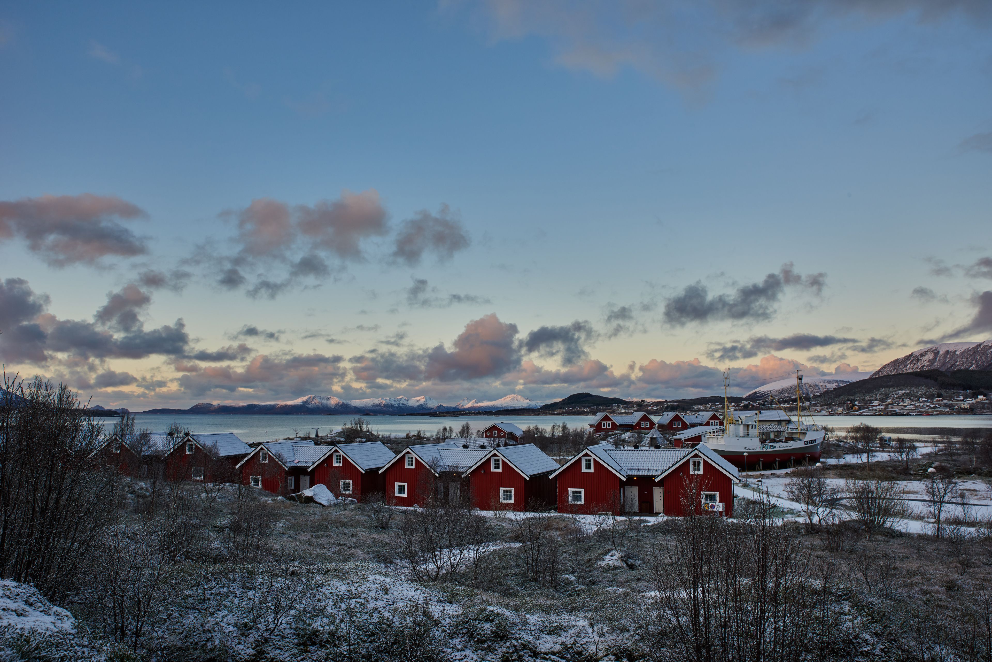 A row of red buildings with a snowy landscape and mountains in the background.