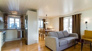 Ein modernes Wohnzimmer mit einem grauen Sofa, einem gelben Sessel und einem Essbereich mit Tisch und Stühlen.
