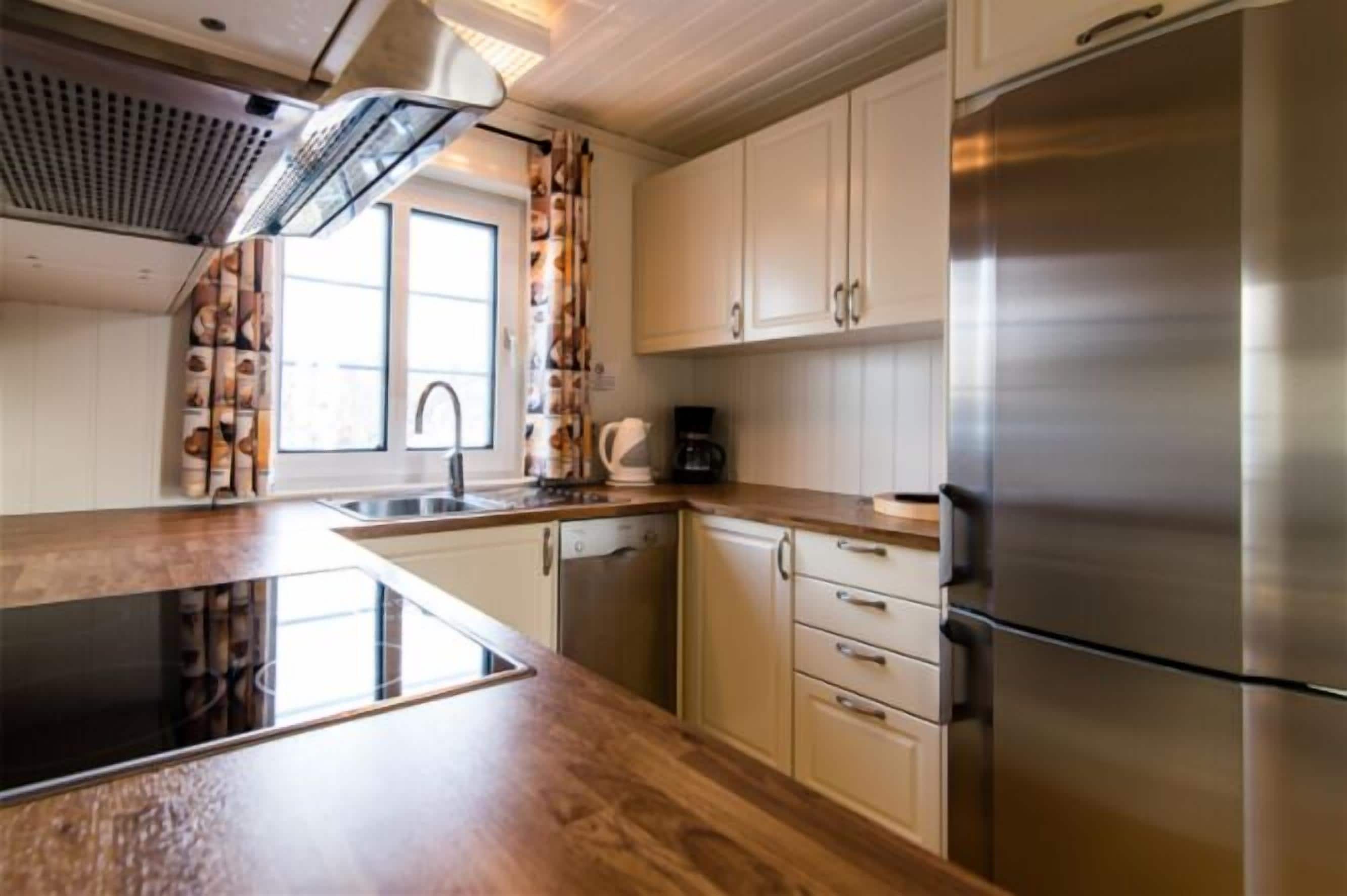 A modern kitchen with stainless steel appliances, wooden countertops, and white cabinetry.