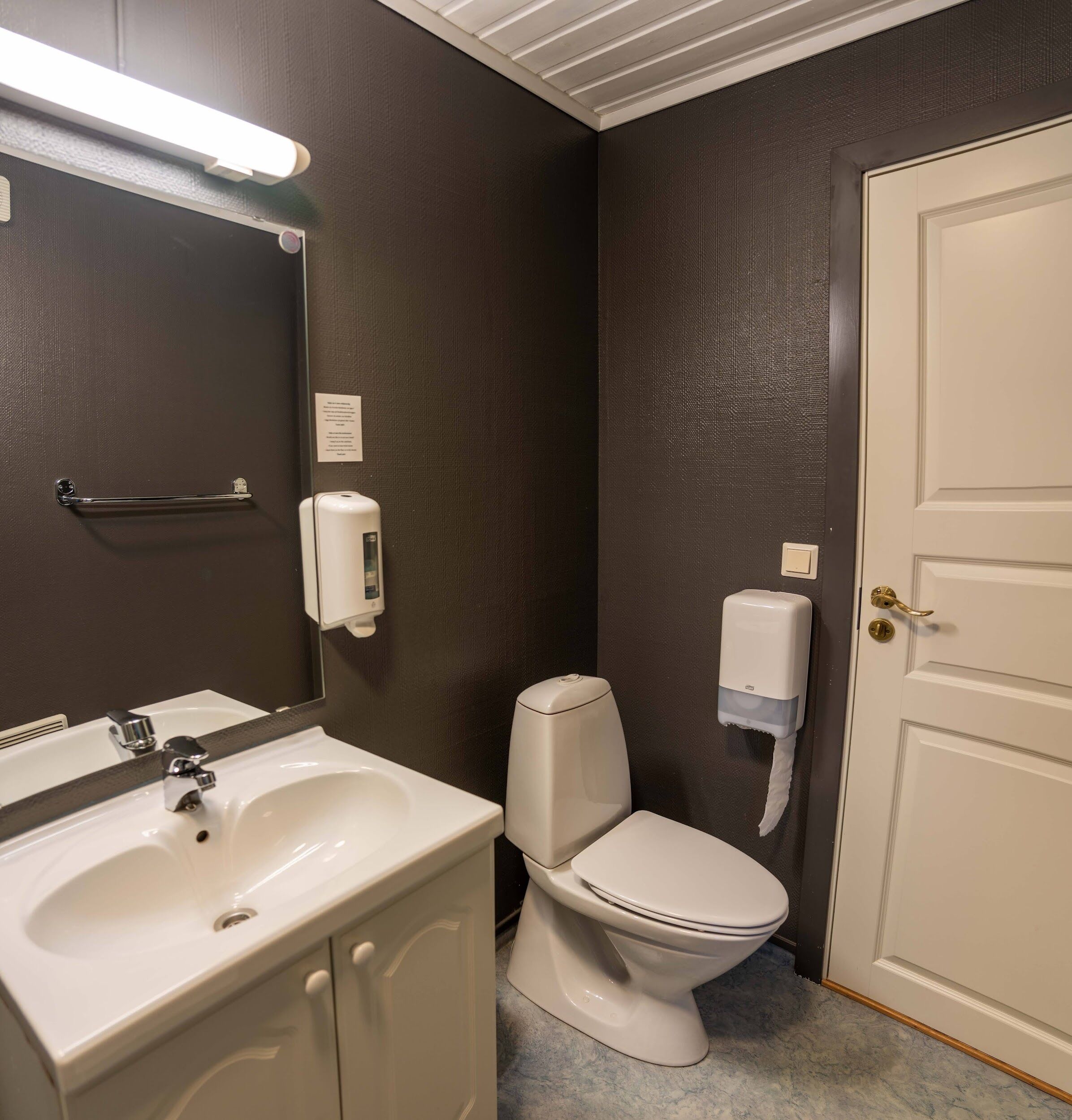 Un baño con un lavamanos blanco, un inodoro y una puerta.