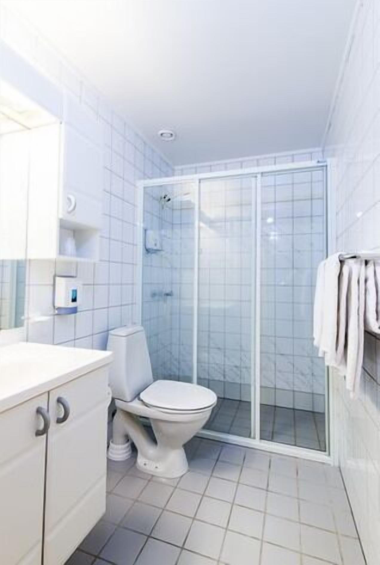A modern bathroom with a toilet, a shower enclosure, and a sink.