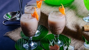 Three glasses of a dessert with a garnish, placed on a table with a green leaf and a spoon. - Citra Suites Surabaya (Surabaya)