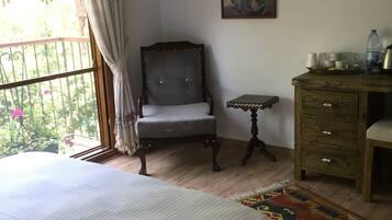 A bedroom with a bed, a chair, a small table, a cabinet, and a painting on the wall.