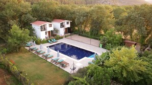 A two-story building with a swimming pool, surrounded by lush greenery and hills. - Piramit Hotel (Fethiye)