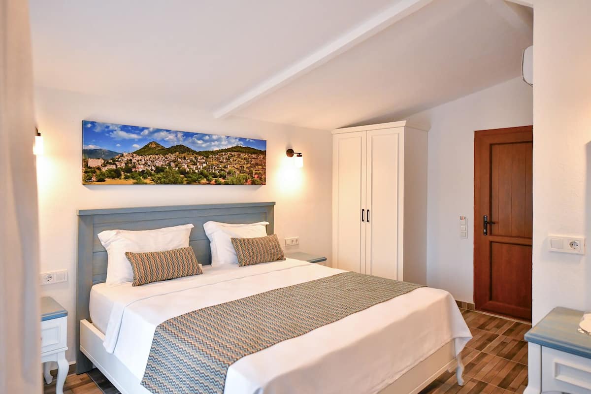 A bedroom with a bed, a wardrobe, and a painting on the wall.