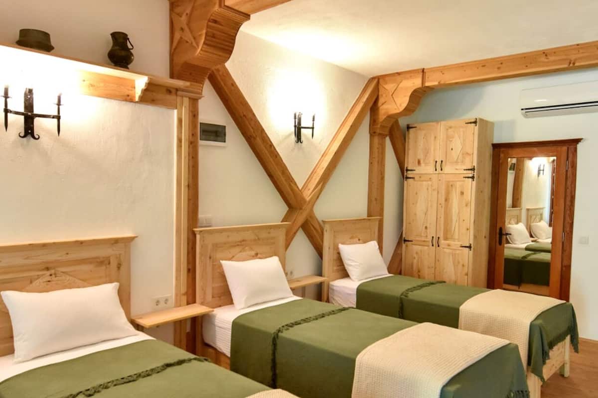 A room with three wooden beds, a wooden ceiling with exposed beams, and a wooden wardrobe.