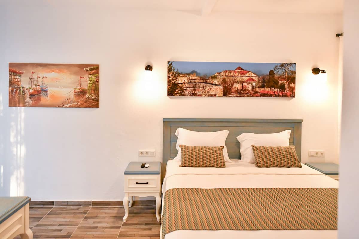 A bedroom with a bed, two nightstands, a bedside table, and two wall-mounted lights.