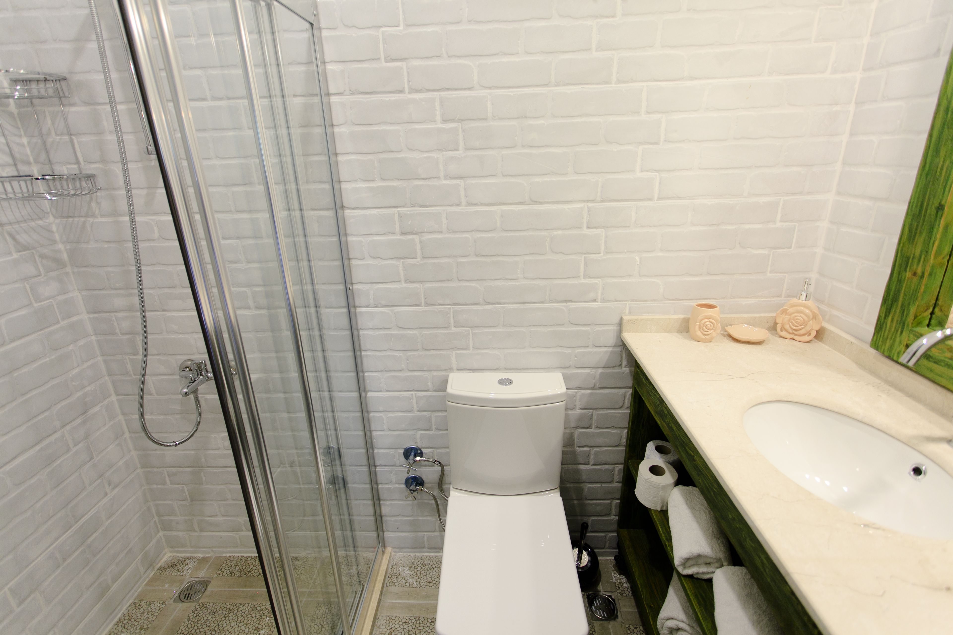 A bathroom with a glass shower enclosure, a white toilet, and a sink with a marble countertop.